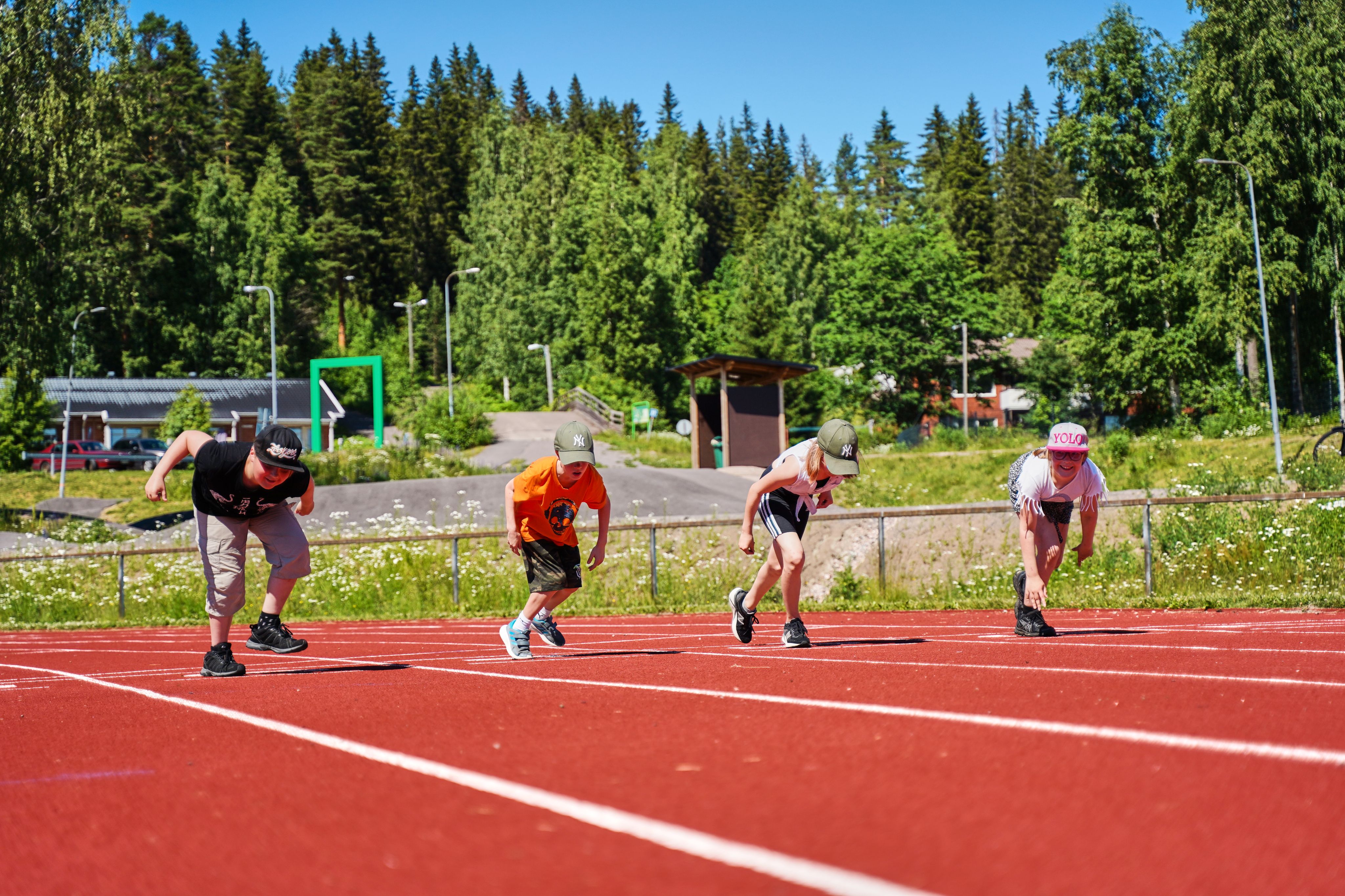 Lapset urheilukentällä juoksukilpailuun lähdössä